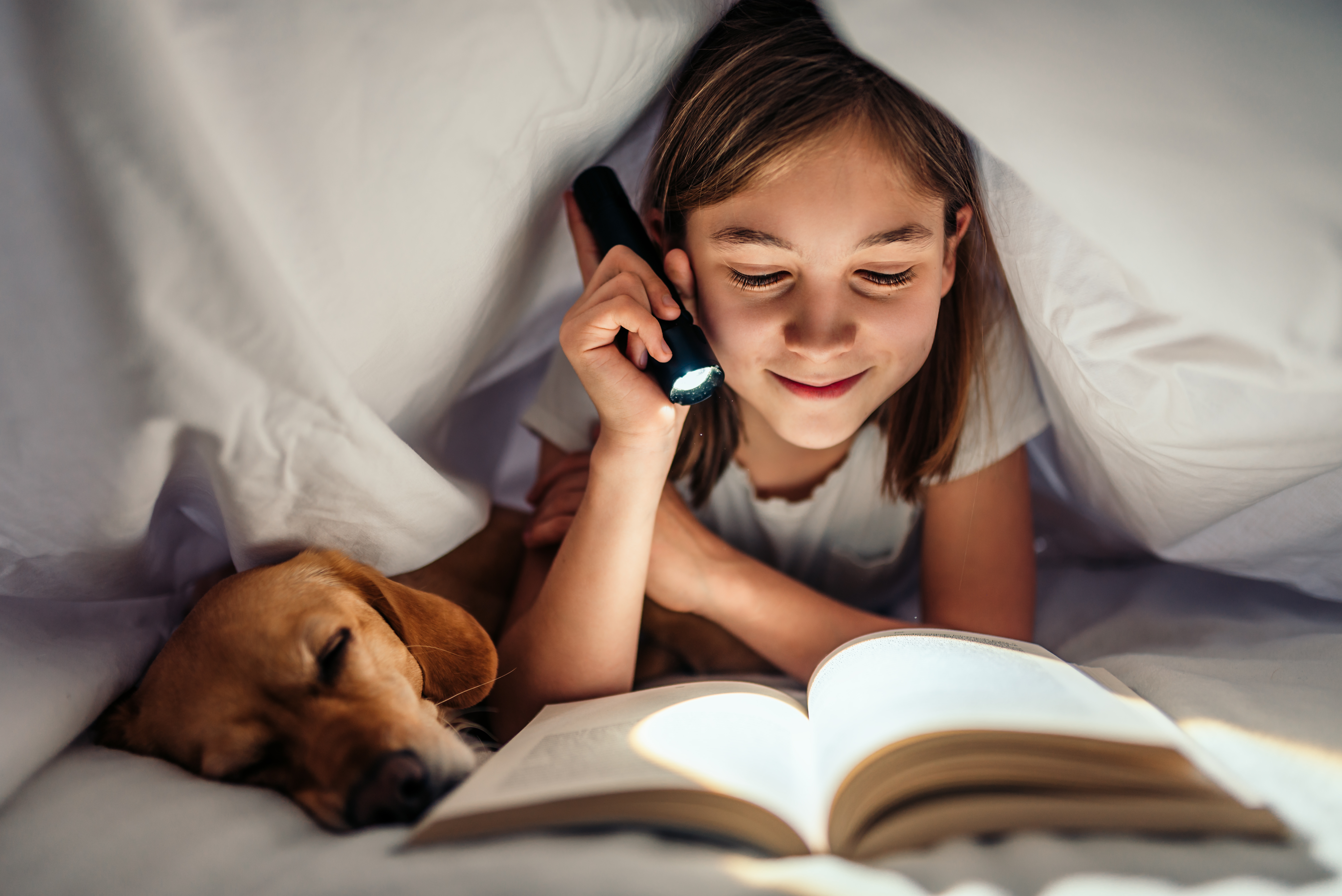 Imaxe nena lendo un libro xunto ao seu cachorro